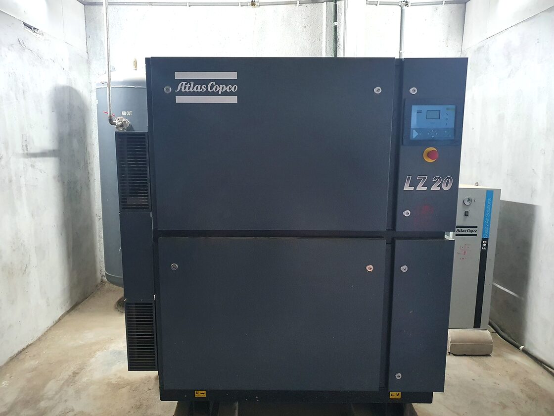 An Atlas Copco LZ 20 oil-free air compressor beside a receiver and a refrigerant dryer in the utility room.